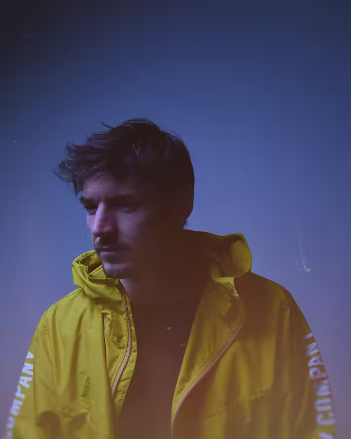 DSCOSTU in a yellow jacket against a blue haze